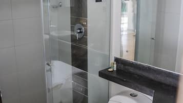 A modern bathroom with a glass-enclosed shower, a white toilet, and a black countertop.