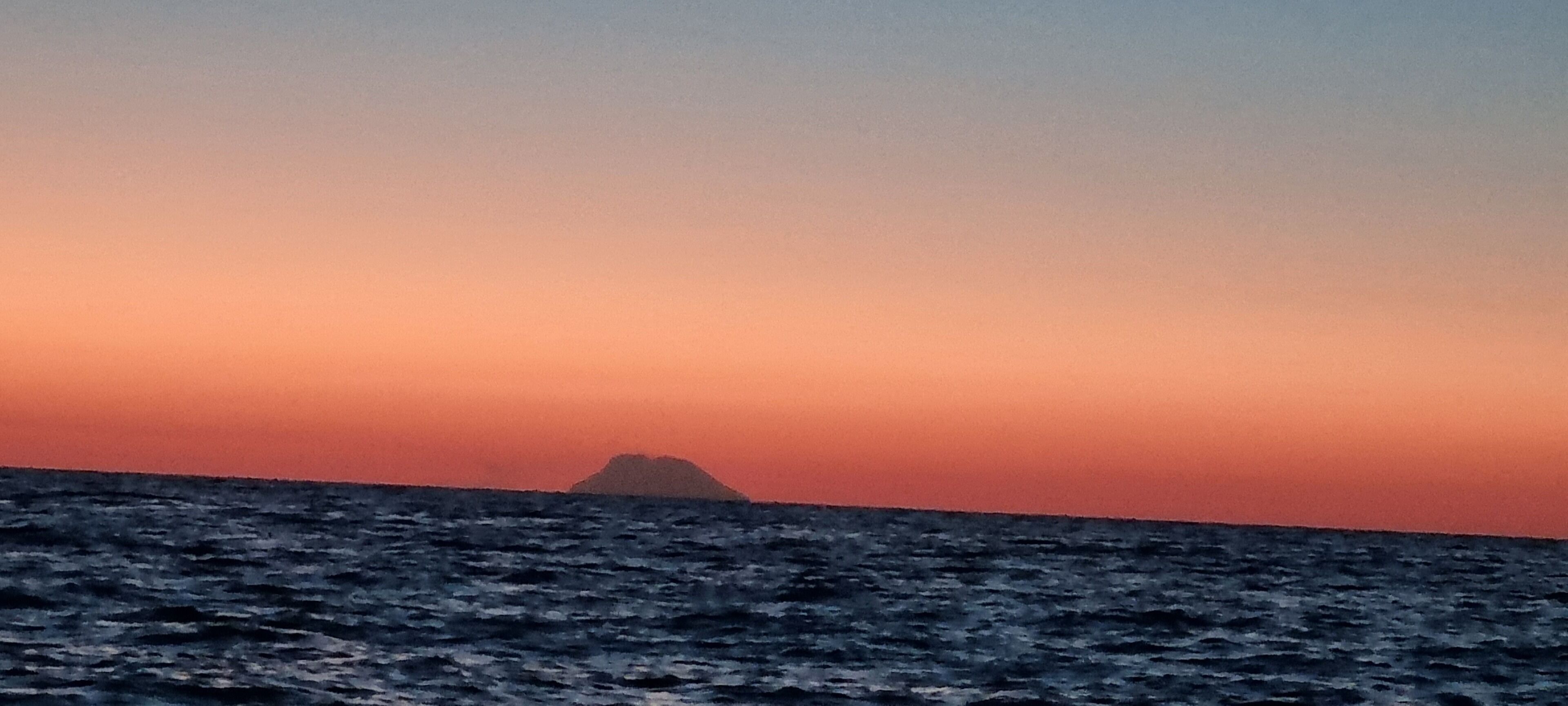 Un capvespre sobre l'oceà amb una petita illa a la distància.