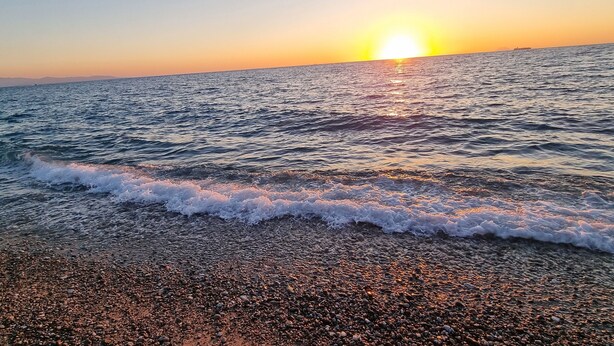 A beach with waves at sunset.