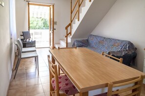 A room with a wooden table, chairs, a sofa, and a staircase.