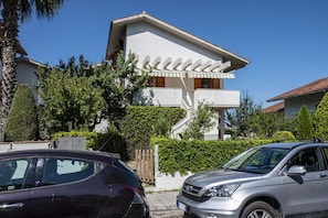 Une maison moderne à deux étages, avec une façade blanche, un balcon et un escalier menant à l’étage supérieur.