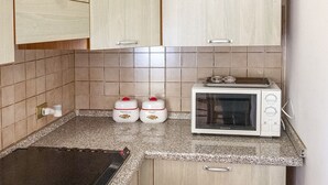 Een keuken met houten kastjes, een magnetron en twee bakken op het aanrecht.