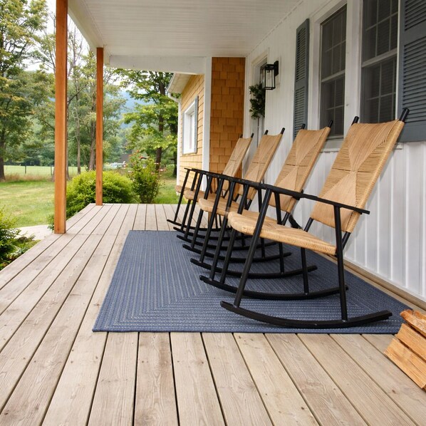 A porch with wooden rocking chairs and a blue mat.