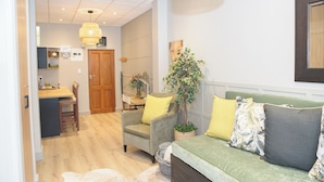 A cozy living area with a sofa, armchairs, a dining table, and a potted plant.