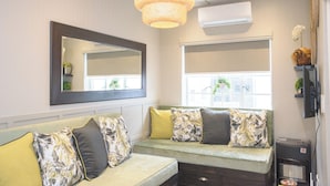 A living room with a sofa, a large mirror, and a ceiling light fixture.