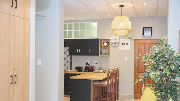 A modern kitchen with a central island, wooden cabinets, and a dining area with bar stools.
