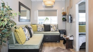 A cozy living room with a sectional sofa, a small coffee table, and a large window.