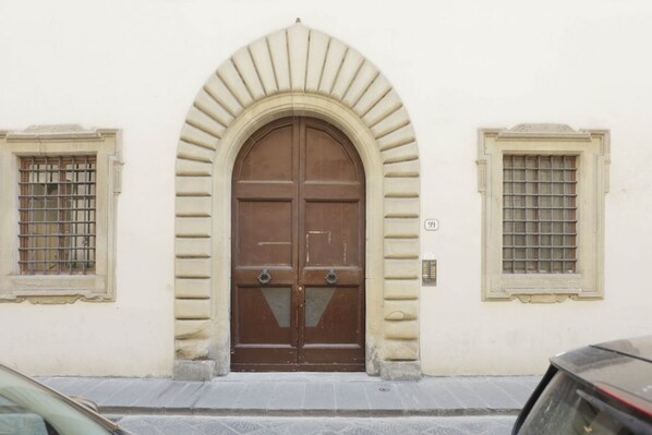 A building with a large arched entrance, two small windows with barred glass, and a door with a handle.