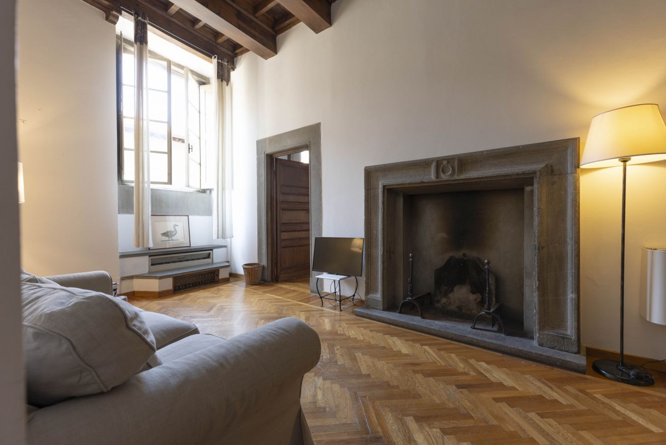 Un salon spacieux avec une cheminée, un plancher en bois et un canapé.