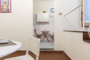 A small, compact kitchen with white cabinets, a red folding table, and a white chair. - Casa Florentia - Florence (Firenze)
