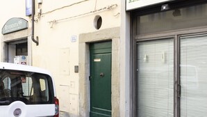 Um carro branco estacionado em frente a um edifício com uma porta verde e uma placa em cima.