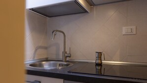 A kitchen with a stainless steel sink, a modern faucet, and a compact coffee maker on the countertop.