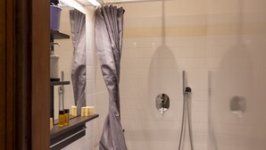 A shower area with a glass door, a handheld showerhead, and a towel rack.