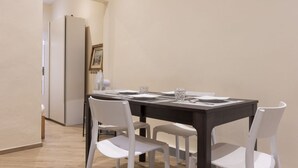 A dining area with a dark wooden table, white chairs, and a framed picture on the wall.