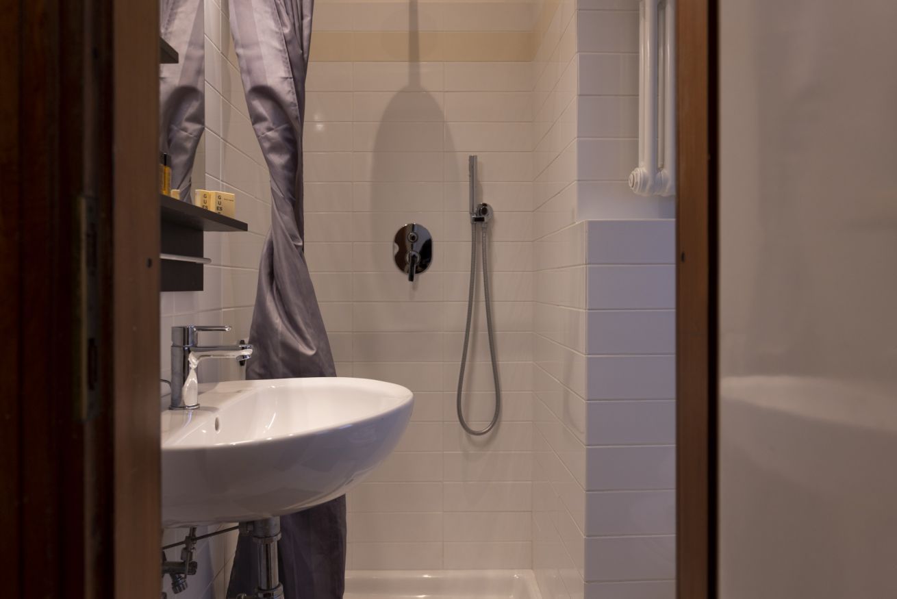 A bathroom with a white sink, a shower, and a towel rack.
