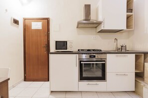 Une cuisine compacte équipée d’un four à micro-ondes, d’une cuisinière, d’un four et dotée d’une porte en bois.