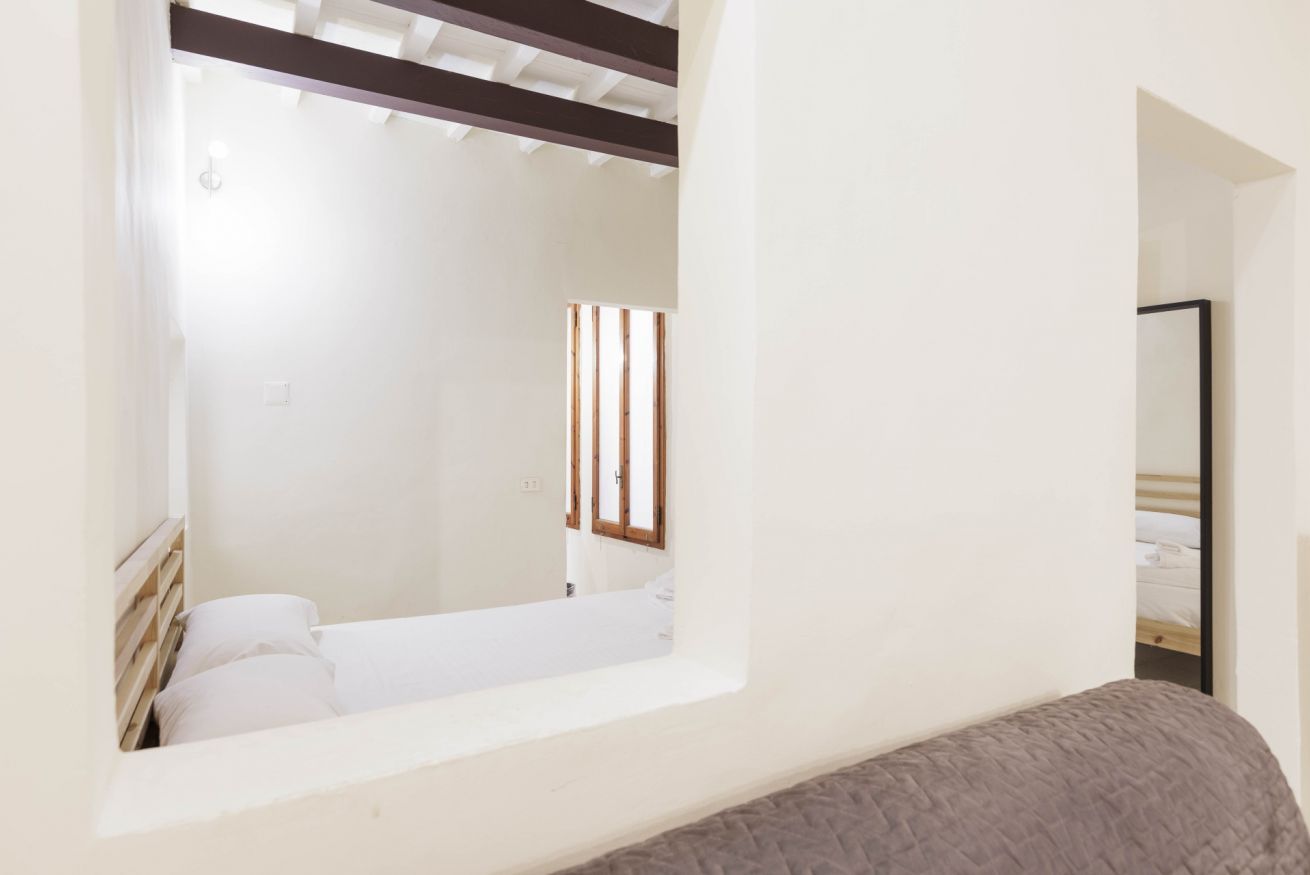 Un dormitorio con una cama, un ventanal y una viga de techo de madera.