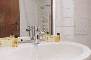 Une salle de bain avec un lavabo blanc, un robinet chromé et des articles de toilette disposés sur le comptoir.