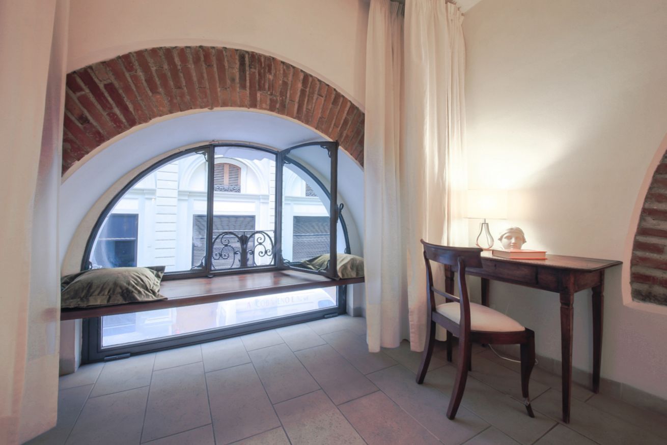A room with a curved window, a wooden desk, and a chair.
