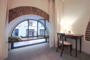 Una habitación con ventanal curvo, un escritorio de madera y una silla.