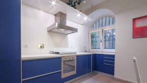 Una cucina moderna con mobili blu, un forno in acciaio inossidabile e una finestra con vista sul verde.