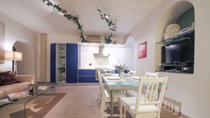 Un soggiorno moderno con un tavolino in vetro, una divano e un'area pranzo con tavolo apparecchiato per quattro persone.