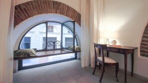 Una stanza con una finestra ad arco, una scrivania in legno e una sedia.