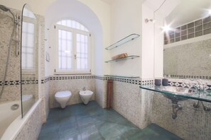 Une salle de bain avec un lavabo en verre, deux toilettes, un bidet et une douche.