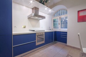 Una cocina moderna con armarios azules, un horno de acero inoxidable y una ventana con vistas a la vegetación.