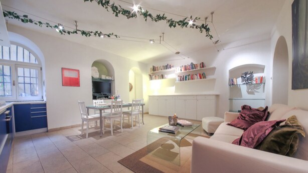 A modern living room with a dining area, kitchen, and bookshelves. - Duomo Deluxe Apartment (Firenze)