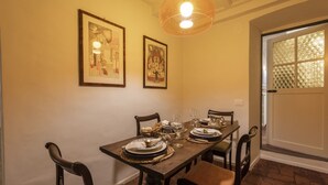 Comedor con una mesa de madera dispuesta para cuatro, obras de arte en la pared y una lámpara colgante.