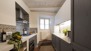 Una cocina estrecha con una isla central, un ventanal y un radiador.