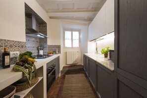 A narrow kitchen with a central island, a window, and a radiator.