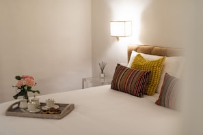 A neatly made bed with a tray of breakfast items, a vase with flowers, and a bedside table with a lamp. - Pitti-Tuscan Charming Apartment (Firenze)
