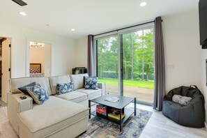 A modern living room with a sofa, coffee table, and bean bag. - Lakefront Catskills Container Home: Private Lake (Swan Lake)