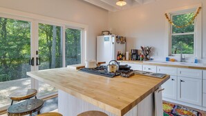 Une cuisine moderne dotée d’un grand îlot central, de meubles blancs et offrant une vue sur l’extérieur.
