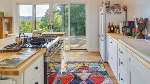 Une cuisine moderne avec une cuisinière à gaz, des plans de travail en bois et un tapis coloré.