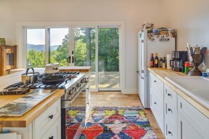 Una cocina moderna con estufa a gas, encimeras de madera y una alfombra colorida.