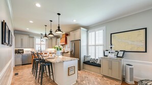 A kitchen with a herringbone floor pattern, a central island with bar stools, pendant lighting, and a seating area with a map on the wall. - Waterfront Vacation Property on the Pamlico (Bath)