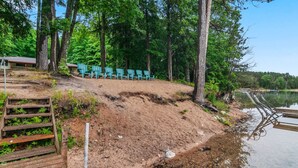 Une terrasse au bord du lac, avec des chaises, un escalier en bois et une jetée qui s’avance dans l’eau.