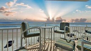 A deck with striped chairs and a view of the beach and ocean. - OE at White Surf Unit 306 (Daytona Beach Shores)
