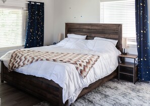 A bed with a wooden headboard, white bedding, and a patterned throw blanket. - Treetop A-frame Cabin, Family Friendly w/a Jacuzzi
 (Lake Arrowhead)