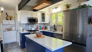 Una cucina moderna con isola centrale, mobili bianchi, frigorifero in acciaio inossidabile e forno a microonde.