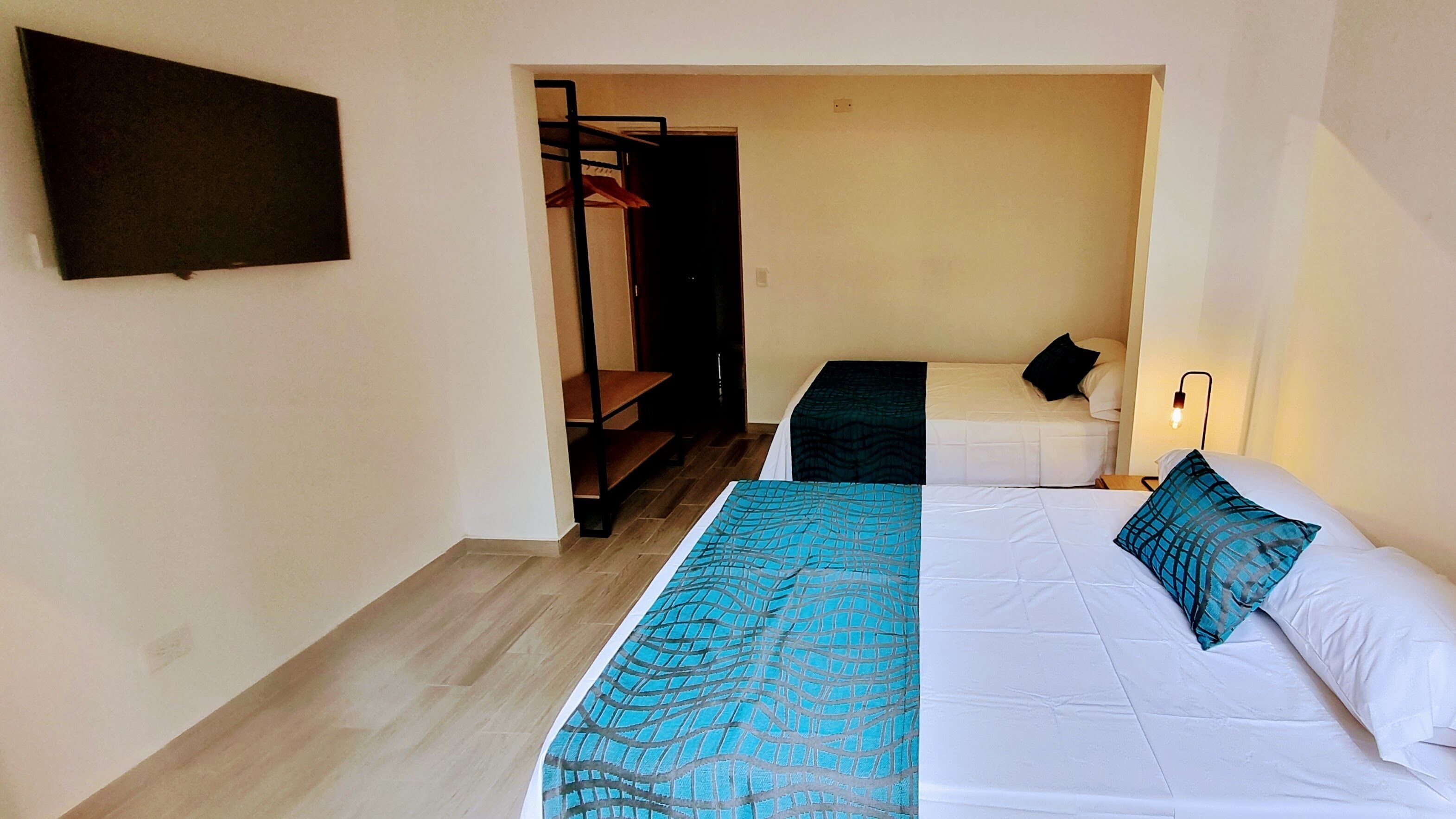 Una habitación con dos camas, un televisor montado en la pared y una escalera que sube a un nivel superior.