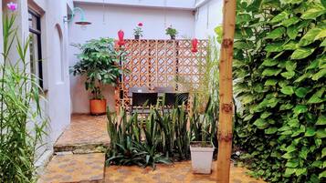 Un patio con un cerramiento de madera con celosías, plantas en macetas y suelo de baldosas.