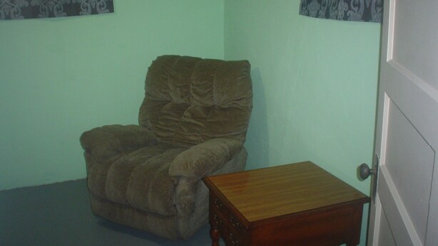 Una habitación con un sillón marrón y una mesita de madera.