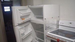 Een kleine keuken met een inbouwkoelkast en oven.