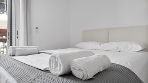 Een hotelkamer met een bed, twee opgerolde handdoeken en een raam met uitzicht.