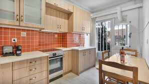 Een moderne keuken met houten kastjes, een inbouwoven en een raam met uitzicht op een tuin.