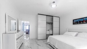 A modern bedroom with a bed, a wardrobe, a dresser, and a mirror. - Hibiscus Charm - 2BR-2BA w/Pool (Kingston)